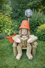 A girl or boy sitting  on a chair reading a book with a solar lamp